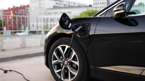 Electric Car Charging At Station, Urban Background
