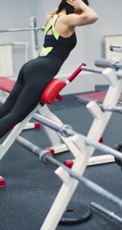 A Fit 40Yearold Woman Performs Back Extensions to Strengthen Her Lower Back at the Gym