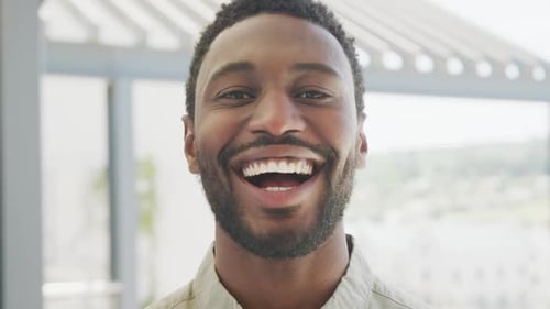 Porträt eines glücklichen afroamerikanischen Geschäftsmannes, der in die Kamera blickt und im Büro lächelt, Zeitlupe