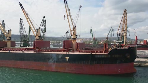 Luftaufnahme eines geschäftigen Seehafens, in dem ein riesiges Frachtschiff ein Massengutfrachter beladen wird