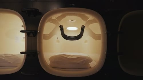 Des lits capsules et une cabine à l'intérieur d'une auberge capsule et d'un hôtel à Tokyo mettent en valeur le style moderne, compact et