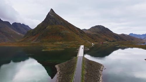 Breathtaking Lofoten Aerial View of a Car on a Bridge with Mountain Backdrop on a Sunny Autumn Day