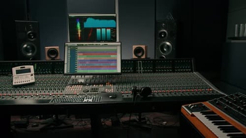 recording studio with a screen with sound wave and volume settings two subwoofers and a console