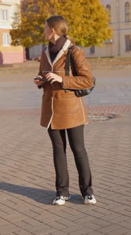 Woman Checks Phone in Urban Setting