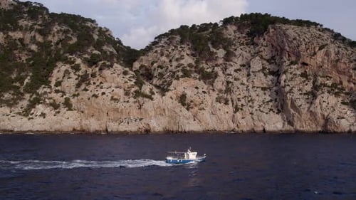 Aerial view of Mediterranean coastline with boat and cliffs, Spain.