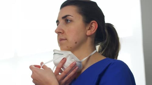 Healthcare worker putting on her protective face mask