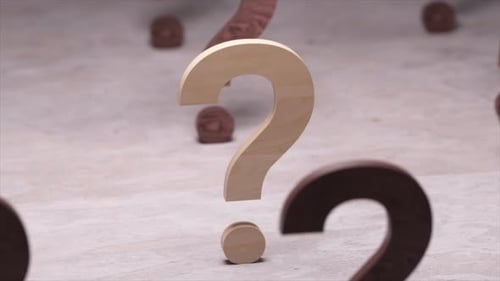 De nombreux points d'interrogation en bois pivotent et se déplacent sur une surface texturée d'une faible profondeur de