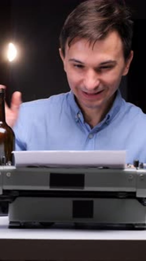Man Typing on Typewriter Drinking From Bottle
