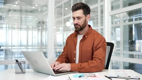 Businessman working on a laptop while sitting at a workplace in business office. Handsome male work