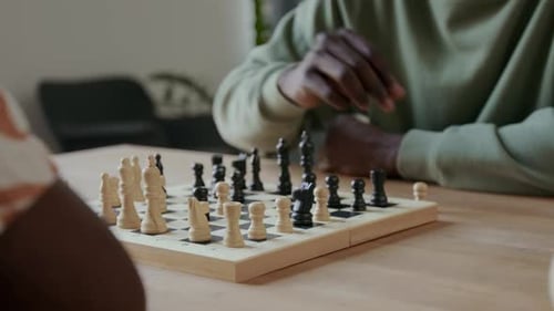 Mãos de dois homens jogando xadrez na mesa de madeira