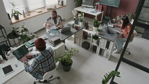 Blick von oben auf ein vielfältiges Team von Softwareentwicklern, die an einem Projekt zusammenarbeiten