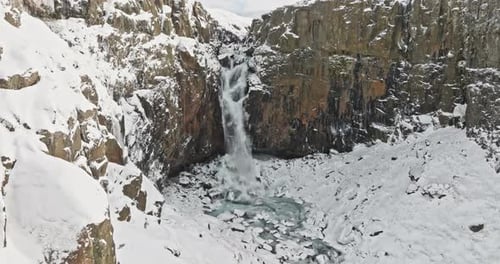 Schneebedeckter Berg mit malerischem Wasserfall und rauem Gelände