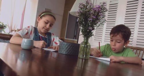 Two Children Drawing at Wooden Table Indoors