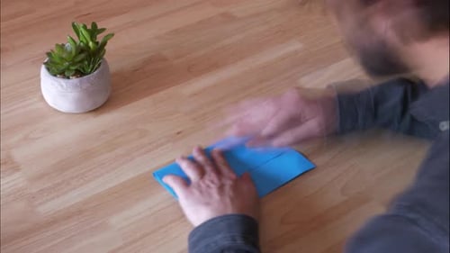 Adult Folding Blue Paper on Wooden Table