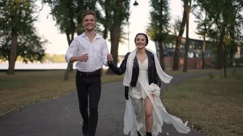 A Joyful Couple Taking a Romantic Stroll Through a Beautiful Park at Sunset Together