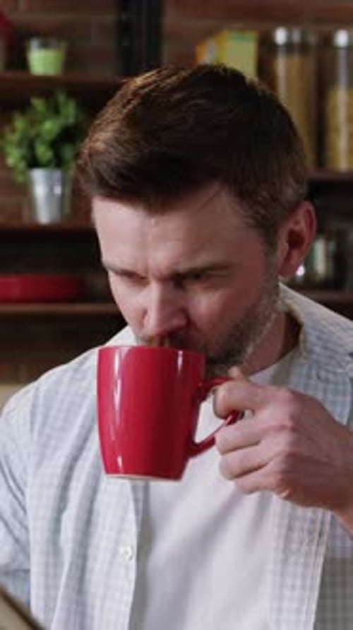 Man Reads Newspaper While Drinking Coffee