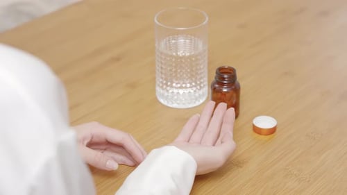 Woman Taking Pills with Glass of Water