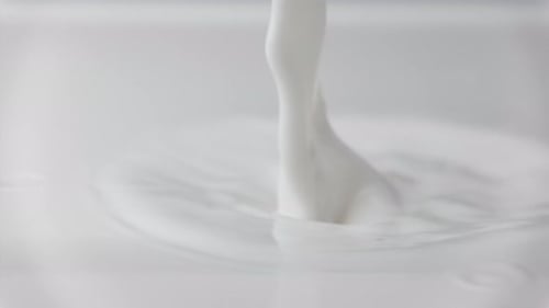 Goutte de lait frais tombant et éclaboussant dans une piscine laiteuse versant du lait au ralenti