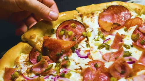 Hand Takes a Slice of Delicious Pepperoni Pizza