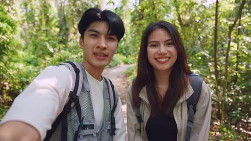 Dois jovens vloggers mochileiros asiáticos se divertem viajando juntos pela floresta.
