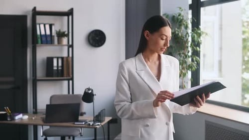 Holding notepad and reading the documents. Businesswoman that in formal clothes is in the office