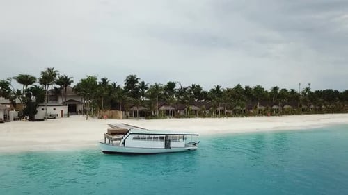 Foto de drone de um iate em um resort nas Maldivas com palmeiras e vilas. Água azul e turquesa. 4K
