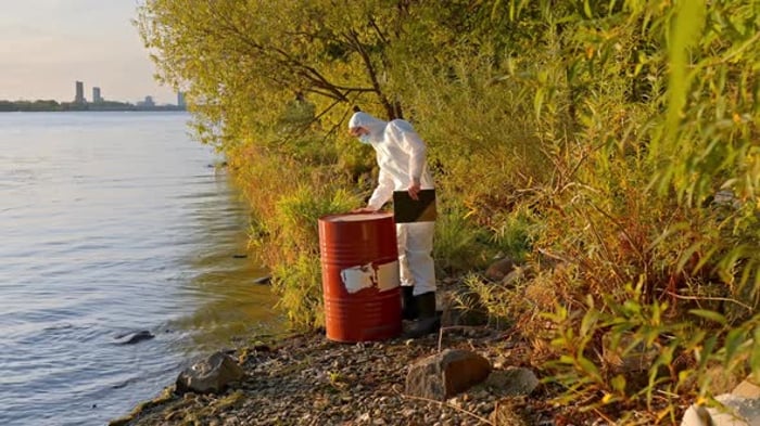 Scientist taking notes beside oil drum at pollution site, Industrial ...