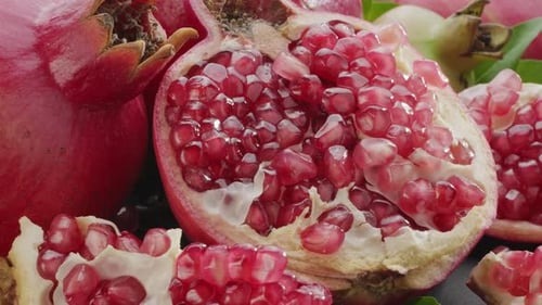 Ripe pomegranate fruits with slices and pomegranate tree leaves slowly move in the frame