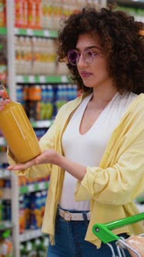 Woman Choosing Juice Bottle at Grocery Store