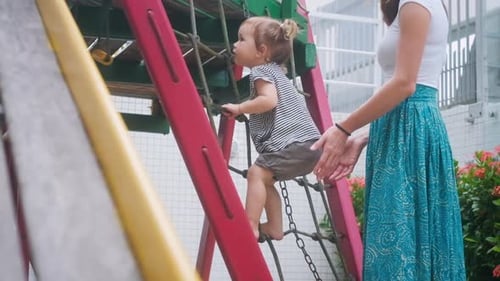 Kind auf dem Spielplatz. Kleinkind hat Spaß auf dem städtischen Spielplatz mit ihrer Mutter