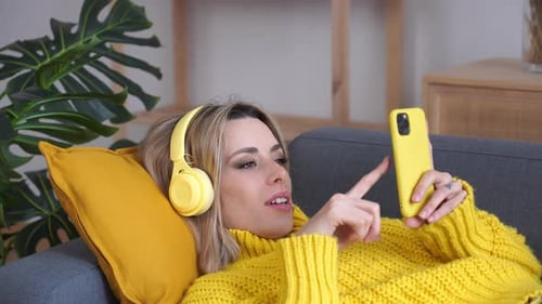 Woman Relaxing on Couch with Smartphone and Headphones