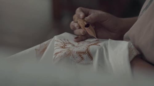 Female hand holding canting for making of batik painting