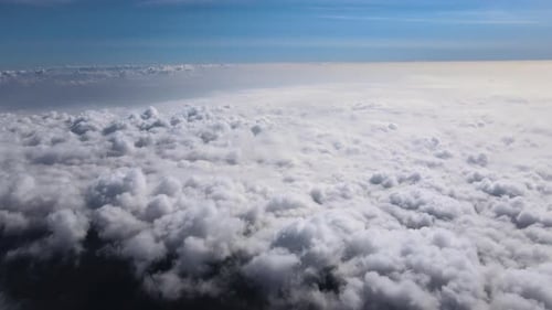 Aerial View From Airplane Window at High Altitude of Earth Covered with White Puffy Cumulus Clouds