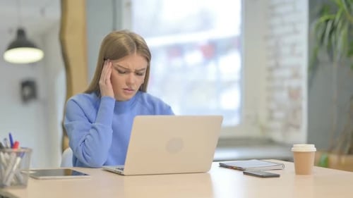 Woman Working on Laptop Experiences Headache in Office