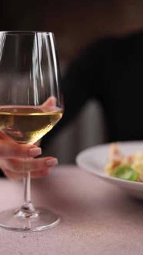 A girl holds a glass of wine. Close-up