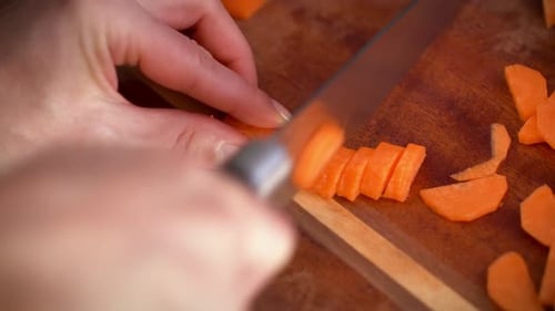 Karotten mit einem Kochmesser auf einem Schneidebrett schneiden