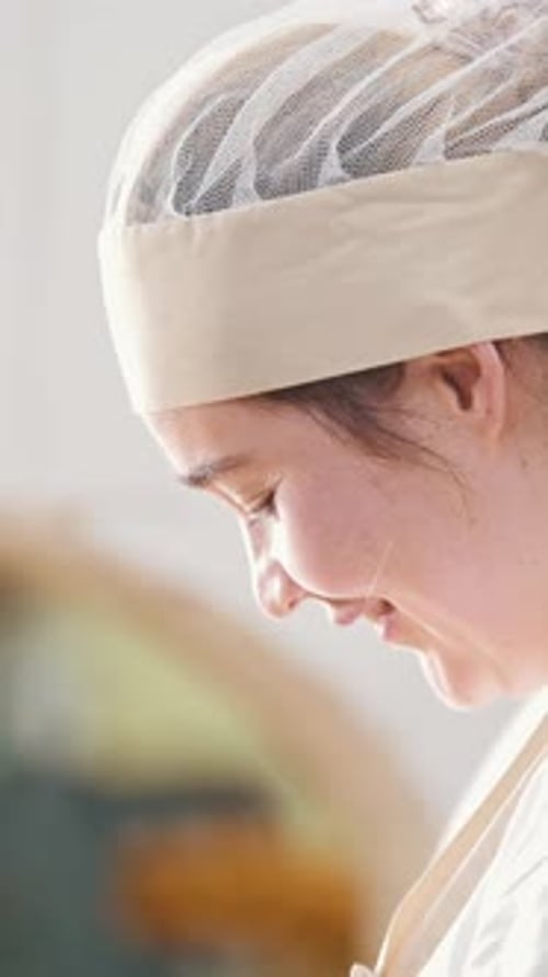 Close-up Profile of a Smiling Woman in a Professional Kitchen Hairnet