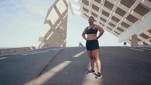 Athletic Woman in Sportswear Stands in Urban Setting