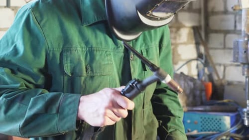 Repairman Holding Soldering Iron and Preparing to Weld Some Metal Details at Garage