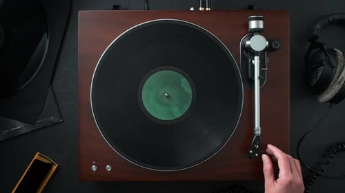 Hand lowers needle on vinyl record player