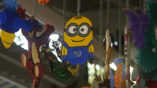 The figure of a Minion made of wood hangs on the ceiling between other figures
