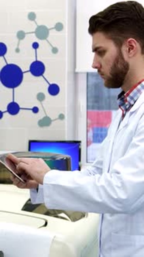 Fokussierter Wissenschaftler überträgt Daten vom Computer auf das Tablet in einem modernen Labor