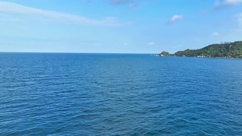 Luftaufnahme über dem blauen Meer mit Welle, blauem Himmel und weißen Wolken. 4K.