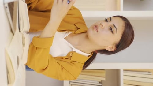 Woman Smiling While Using Smartphone at Desk