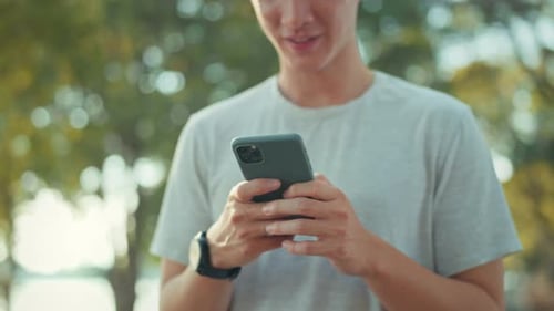 Close-up hand of man holding mobile phone at public park, Male using smartphone