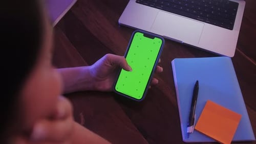 Back View of Woman Holding Chroma Key Green Screen Smartphone Watching Content Touching or Swiping