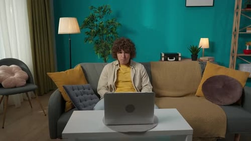 Young Man Talking on Laptop Video Call at Home