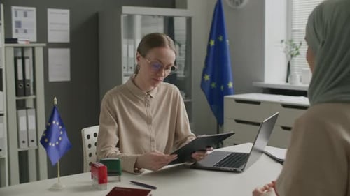 Female Consular Officer Interviewing Woman in Hijab at EU Embassy