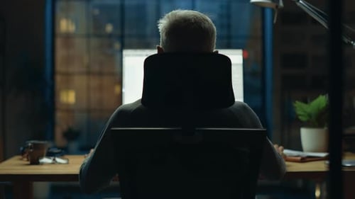 Vue arrière de l'homme d'affaires assis à son bureau à l'aide d'un ordinateur de bureau. Studio de bureau élégant