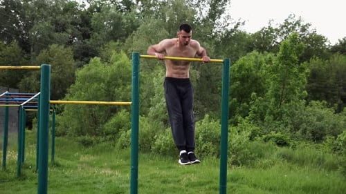 Strong and Muscular Man Doing Exercises on Horizontal Bar at Nature Hardy Shirtless Sportsman